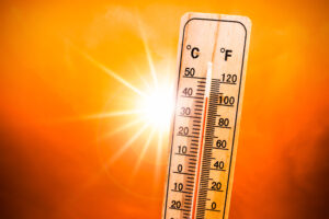 Holz-Thermometer, das 49 Grad anzeigt, vor einem orangen Hintergrund mit Sonne